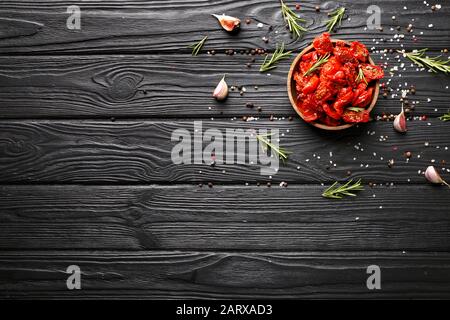 Plate with dried tomatoes and spices on wooden table Stock Photo