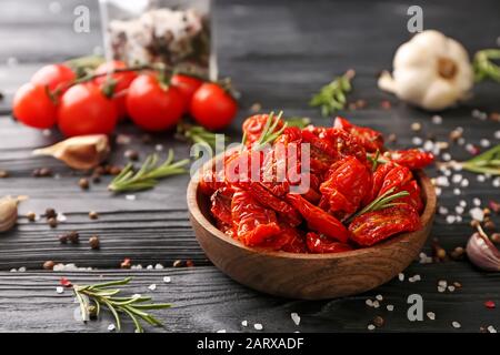 Plate with dried tomatoes and spices on wooden table Stock Photo