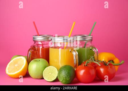 Mason jars of fresh juices with ingredients on color background Stock Photo