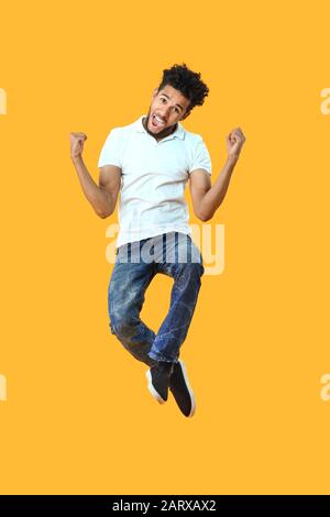 Portrait of jumping African-American man on color background Stock Photo