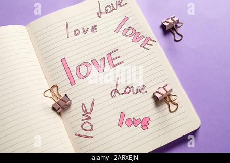 Open notebook with written words LOVE on color background Stock Photo