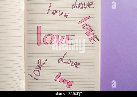 Open notebook with written words LOVE on color background Stock Photo