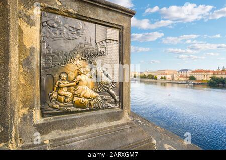 The bronze plaque depicting St. John of Nepomuk being thrown off the bridge on Charles Bridge over the Vltava River in Prague. Tourists rub to return Stock Photo