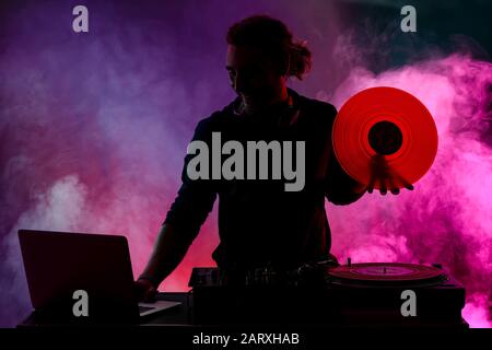 Silhouette of male dj playing music in nightclub Stock Photo