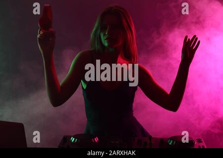 Silhouette of female dj playing music in nightclub Stock Photo