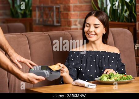 Woman paying bill in restaurant through terminal Stock Photo