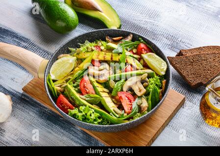 Frying pan with tasty avocado salad on wooden table Stock Photo