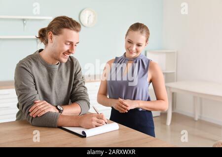 Young man signing a sale and purchase contract in his new house Stock Photo