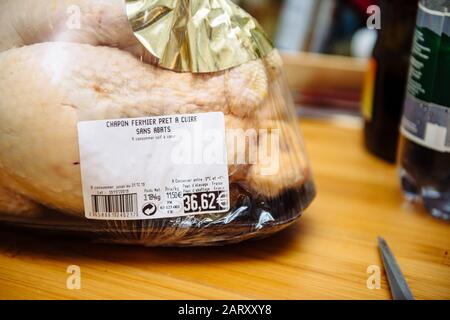 Paris, France - Dec 24, 2019: Price tag of 36,62 Euros on the packaging of fresh Capon Chapon cockerel meat on kitchen wooden top Stock Photo