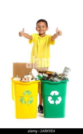 Little African-American boy showing thumb-up near containers with trash on white background. Concept of recycling Stock Photo