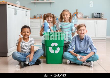 Little children and container with trash in kitchen. Concept of recycling Stock Photo