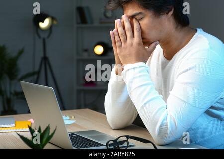Tired Asian programmer working late in evening Stock Photo