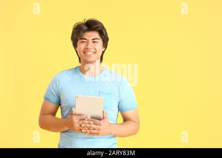 Male Asian programmer with tablet computer on color background Stock Photo