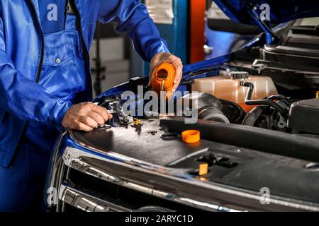 Male mechanic refilling car oil in service center Stock Photo