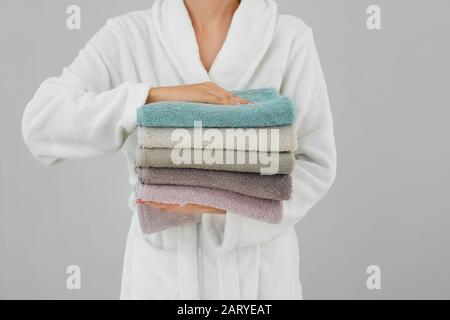 Woman holding stack of towels on light background Stock Photo