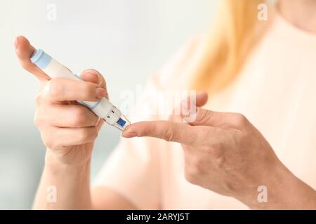 Diabetic woman taking blood sample with lancet pen at home, closeup Stock Photo