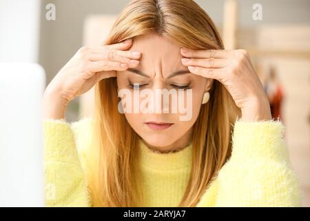 Mature woman suffering from head ache in office Stock Photo