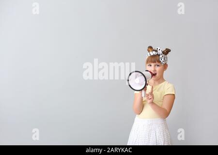 Cute little girl with megaphone on light background Stock Photo