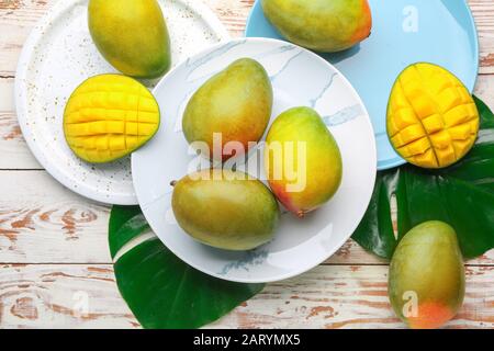 Plates with sweet ripe mangoes on wooden table Stock Photo