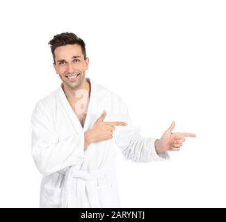 Handsome man in bathrobe pointing at something on white background Stock Photo