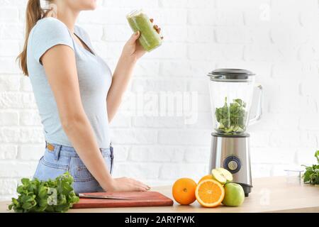 Woman with healthy homemade smoothie in kitchen Stock Photo