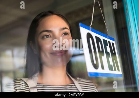 Smiling woman behind shop open sign Stock Photo
