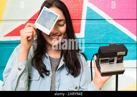 Smiling woman holding photograph and Polaroid camera Stock Photo