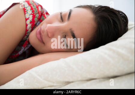 Sleeping woman lying down on bed Stock Photo