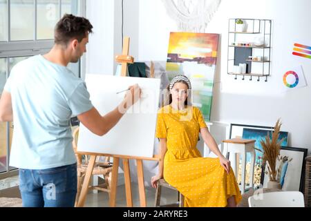 Young woman posing for male artist in studio Stock Photo
