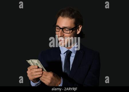 Portrait of handsome businessman with money on dark background Stock Photo