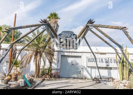 A gigantic spider sculpture made with welded parts including a Volkswagen Beetle stands outside of a business along Indian Canyon Rd in Palm Springs. Stock Photo