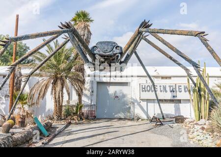 A gigantic spider sculpture made with welded parts including a Volkswagen Beetle stands outside of a business along Indian Canyon Rd in Palm Springs. Stock Photo