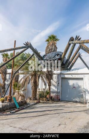 A gigantic spider sculpture made with welded parts including a Volkswagen Beetle stands outside of a business along Indian Canyon Rd in Palm Springs. Stock Photo