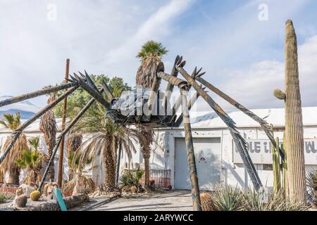 A gigantic spider sculpture made with welded parts including a Volkswagen Beetle stands outside of a business along Indian Canyon Rd in Palm Springs. Stock Photo