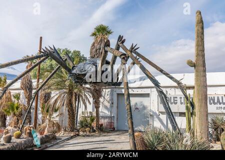 A gigantic spider sculpture made with welded parts including a Volkswagen Beetle stands outside of a business along Indian Canyon Rd in Palm Springs. Stock Photo