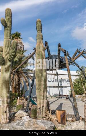 A gigantic spider sculpture made with welded parts including a Volkswagen Beetle stands outside of a business along Indian Canyon Rd in Palm Springs. Stock Photo