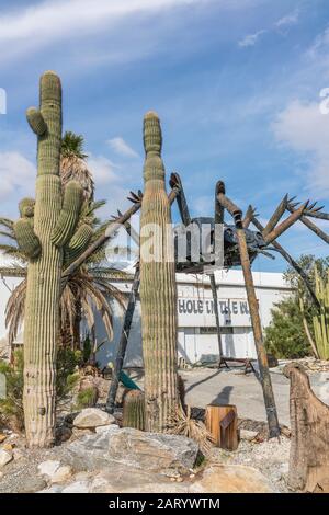 A gigantic spider sculpture made with welded parts including a Volkswagen Beetle stands outside of a business along Indian Canyon Rd in Palm Springs. Stock Photo