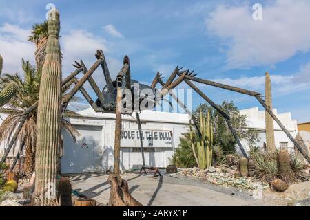 A gigantic spider sculpture made with welded parts including a Volkswagen Beetle stands outside of a business along Indian Canyon Rd in Palm Springs. Stock Photo