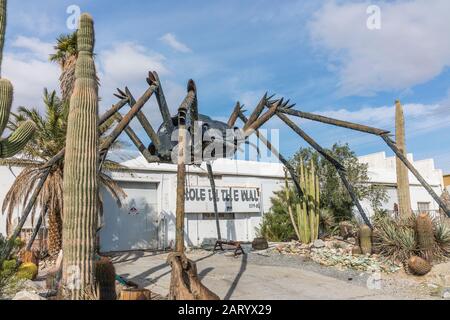 A gigantic spider sculpture made with welded parts including a Volkswagen Beetle stands outside of a business along Indian Canyon Rd in Palm Springs. Stock Photo