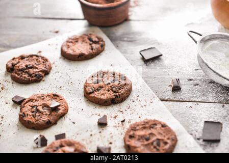 Tasty chocolate chip cookies with flour on wooden background