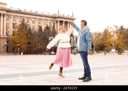 Happy mature couple dancing outdoors on autumn day Stock Photo