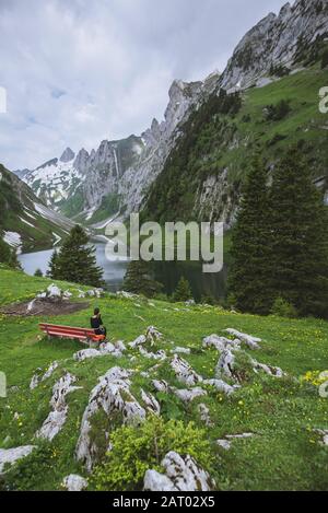 Woman sitting on bench by mountains in Appenzell, Switzerland Stock Photo