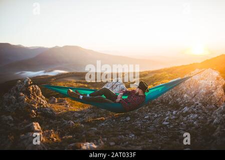 Man lying on hammock in mountain range Stock Photo