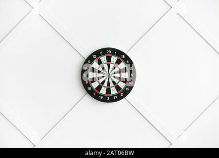Dartboard hanging on light wall Stock Photo