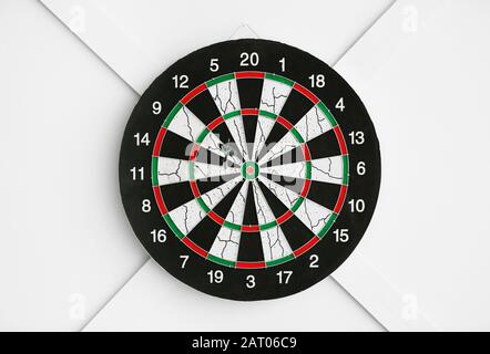 Dartboard hanging on light wall Stock Photo