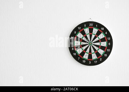 Dartboard hanging on light wall Stock Photo