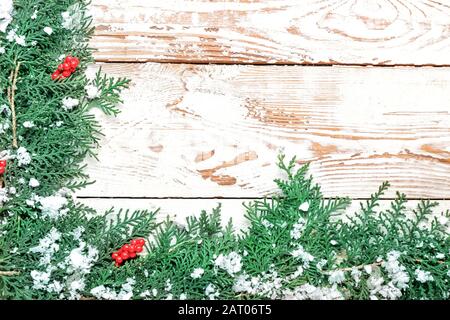Green coniferous branches with snow on white wooden background Stock Photo