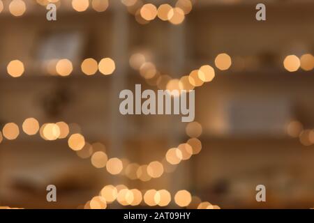 Beautiful glowing garland on shelving unit, blurred view Stock Photo