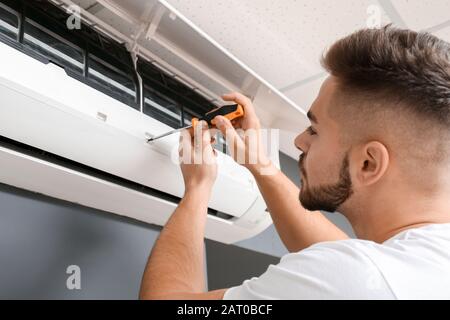 Male technician repairing air conditioner indoors Stock Photo