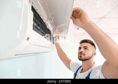 Male technician repairing air conditioner indoors Stock Photo